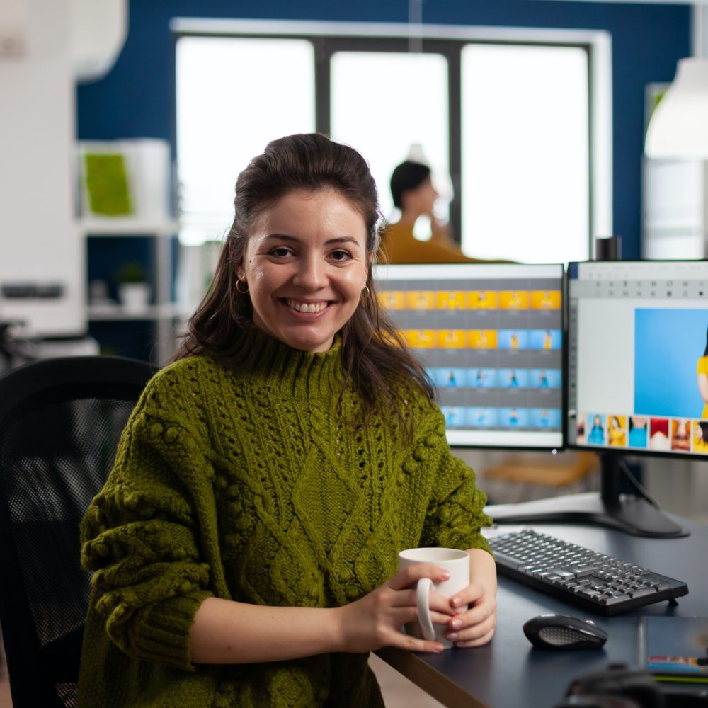 Woman retoucher looking at camera smiling working in creative media agency